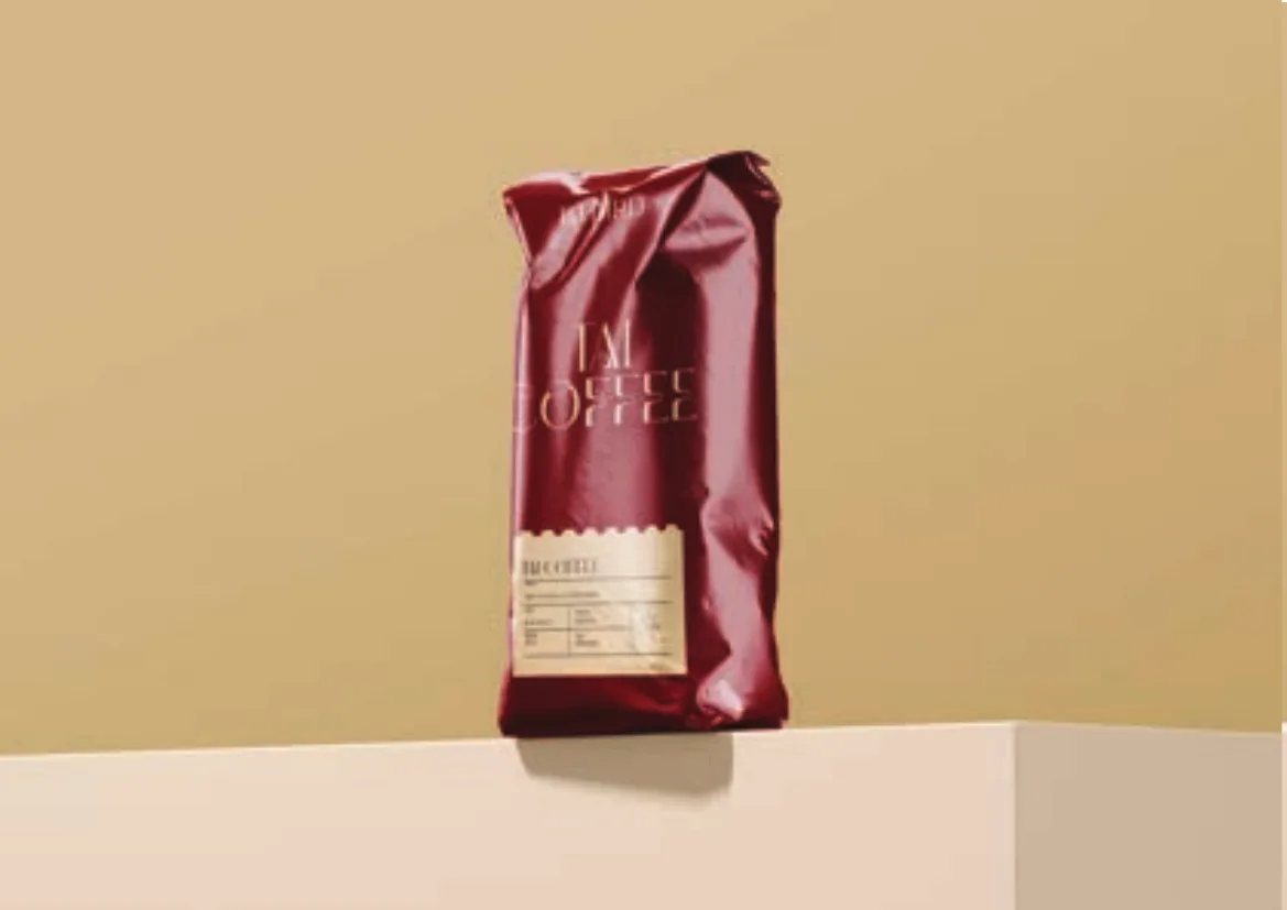 Crimson foil Tai Coffee bag on a tan plinth